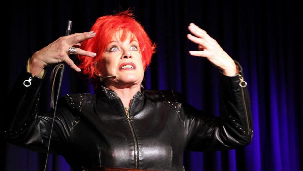 Lisa Fitz als weltoffene Pressedame Inge von Stein mit knatschroter Kurzhaarfrisur und engem Lederdress.© Monika Salzmann Lisa Fitz als weltoffene Pressedame Inge von Stein mit knatschroter Kurzhaarfrisur und engem Lederdress.© Monika Salzmann